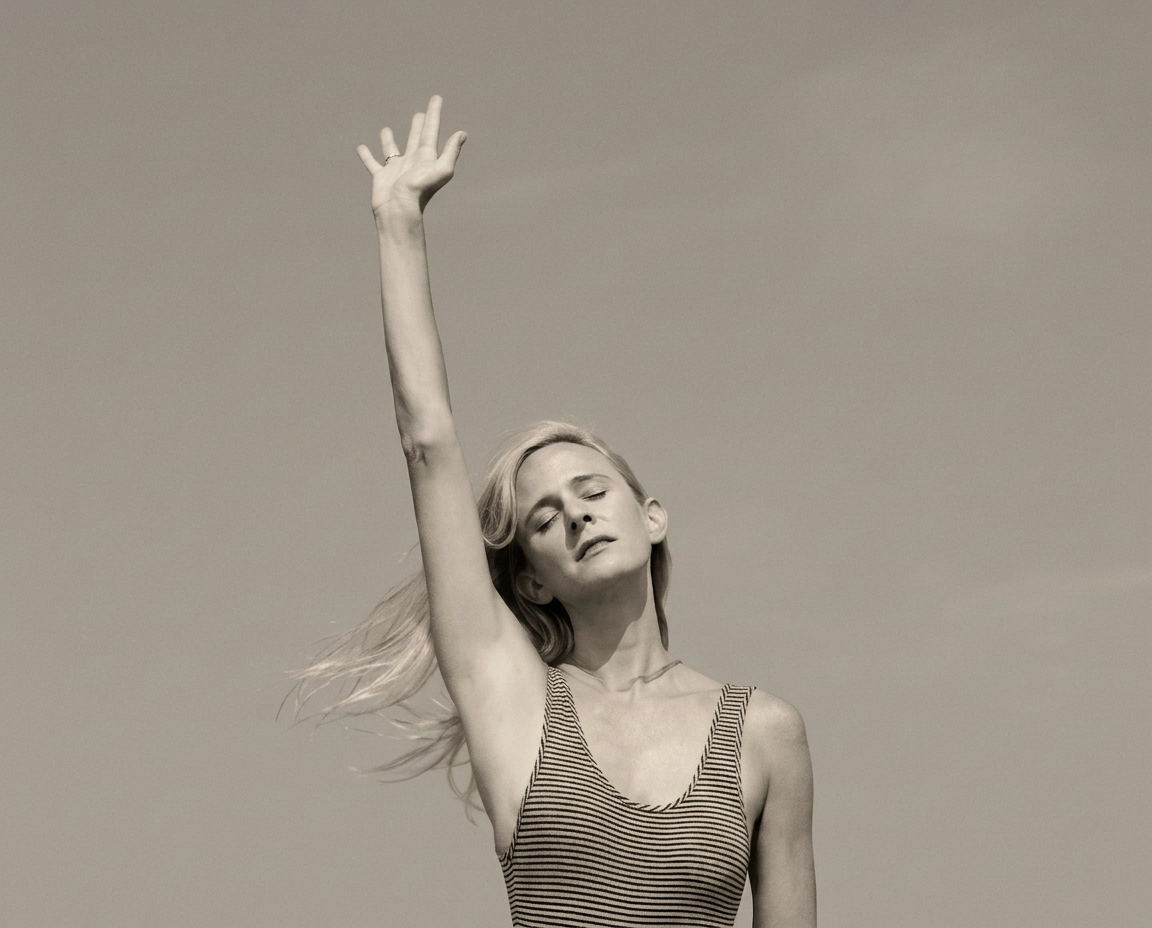 Andrea on a rooftop reaching toward the sky in a moment of movement